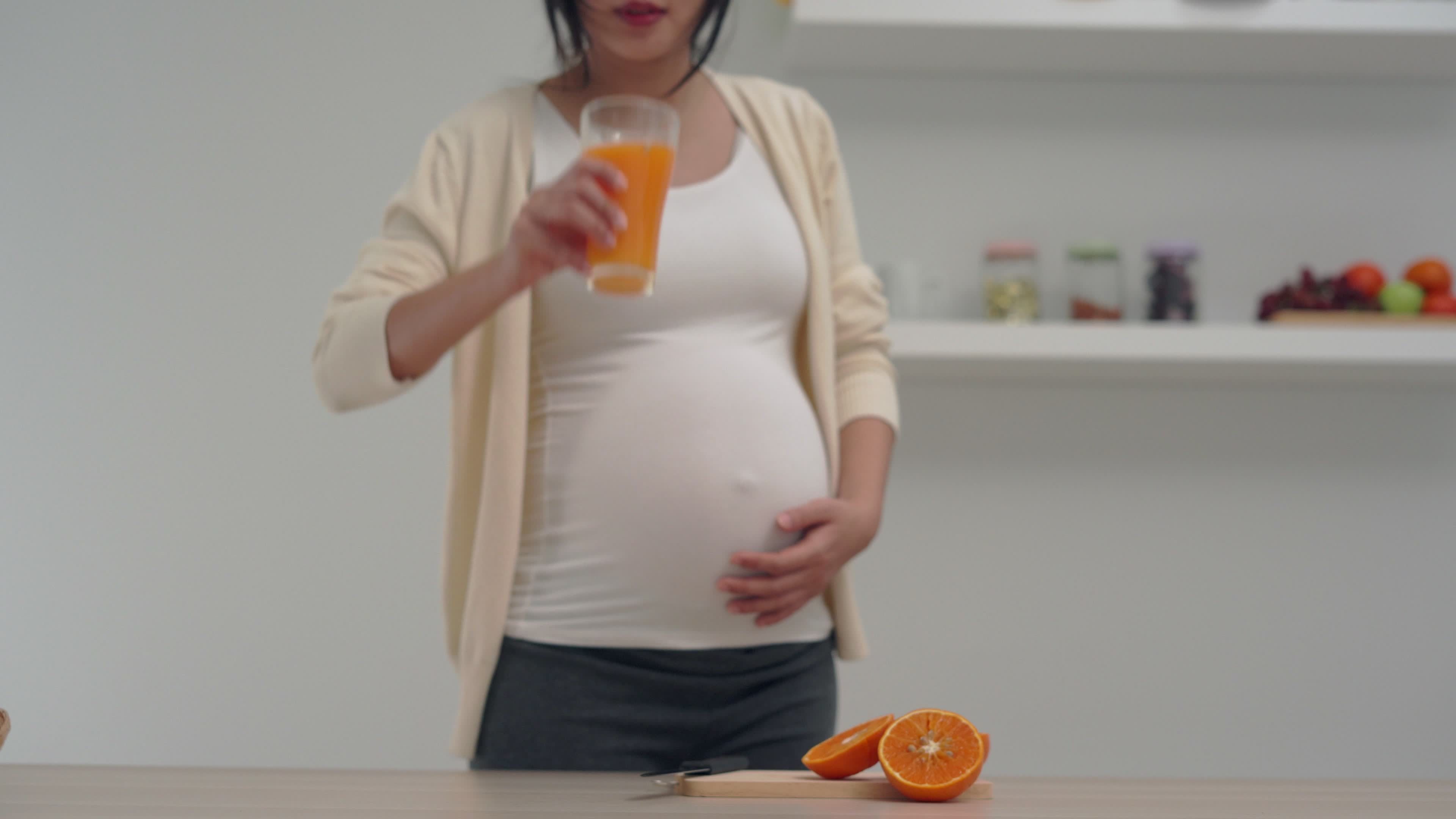 A pregnant woman is juicing orange juice to add vitamins to her unborn