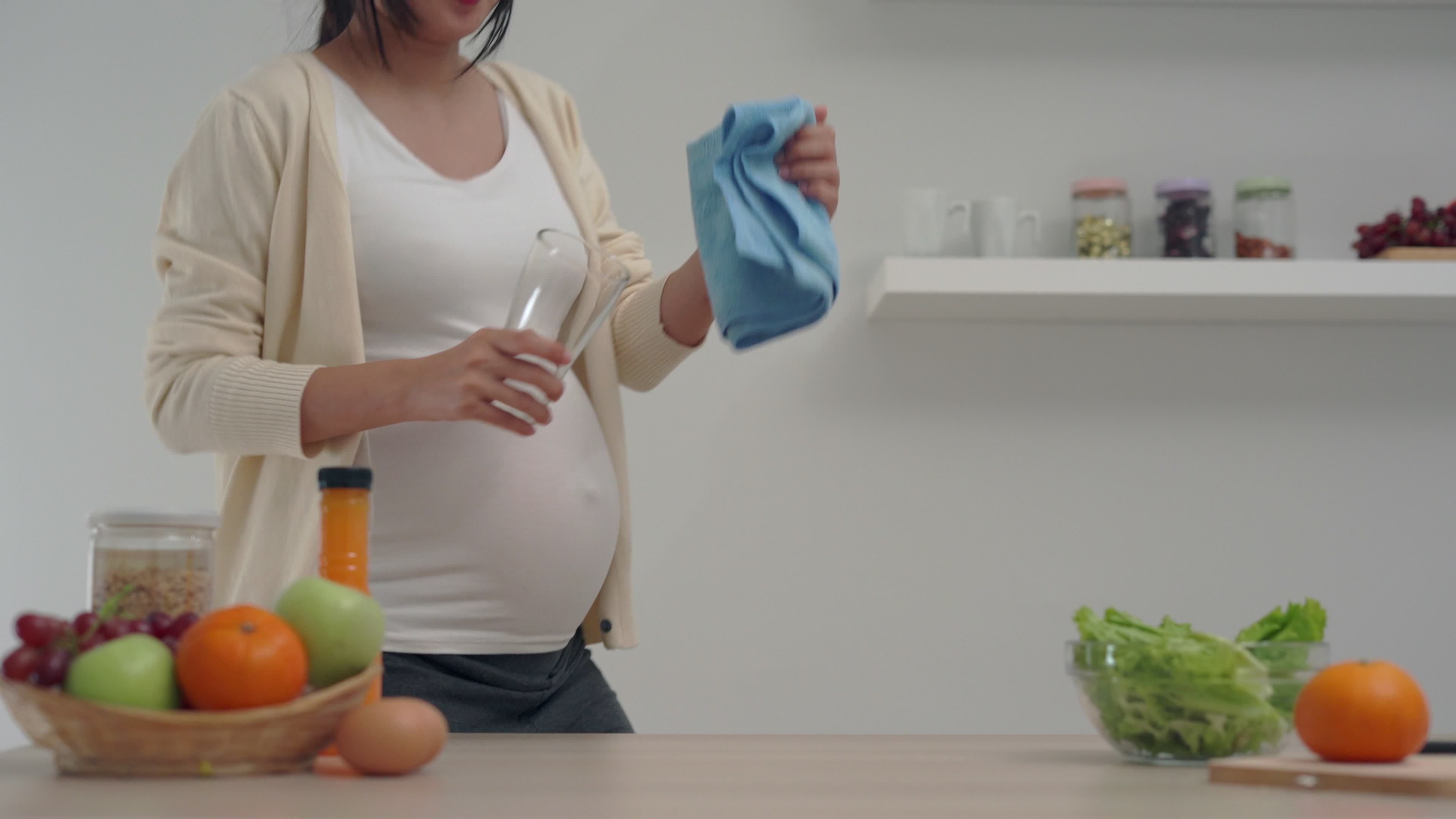 A pregnant woman in a good mood is happily clean the kitchen and clean