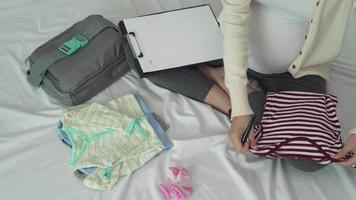 mãe está dobrando roupas de bebê para se preparar para o próximo bebê. uma mulher grávida está verificando o necessário para o recém-nascido. mães registram entre de pano para bebê. video