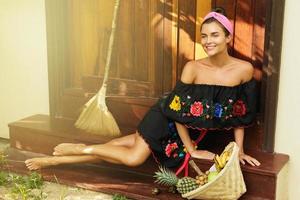 Beautiful woman sitting on the doorstep beside her house photo