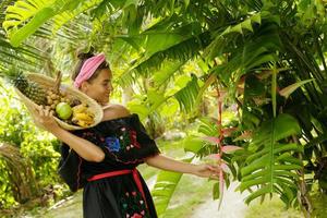 Happy young woman with a basket full of exotic fruits photo