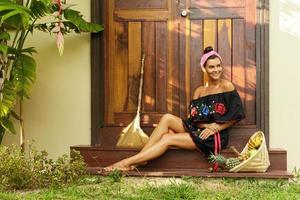 Beautiful woman sitting on the doorstep beside her house photo