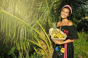 mujer joven feliz con una cesta llena de frutas exóticas foto