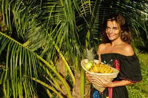 mujer joven feliz con una cesta llena de frutas exóticas foto