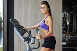 deportivo es mujer usando entrenador elíptico en el gimnasio foto