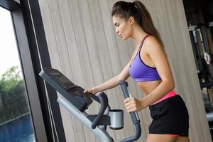 Sporty is woman using elliptical trainer in GYM photo