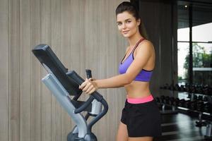 Sporty is woman using elliptical trainer in GYM photo