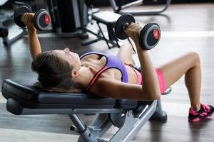 Woman working out with dumbbells in gym. Incline bench press. photo