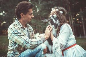 Young and happy couple and funny friendly goat photo
