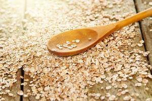 Uncooked oatmeal and wooden spoon on the table photo