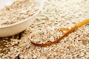 Uncooked oatmeal, white bowl and wooden spoon on the table photo