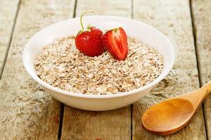 Oatmeal flakes and strawberry on the wooden table photo