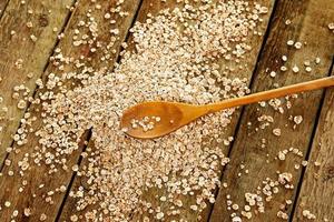 avena cruda y cuchara de madera sobre la mesa foto