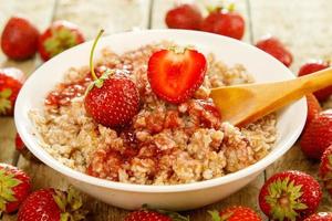 Cooked oatmeal, berries and strawberry jam on the table photo