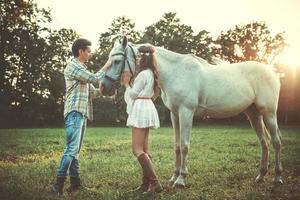 joven pareja feliz y hermoso caballo blanco foto