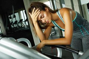 Woman on the treadmill with overtraining symptoms in gym photo