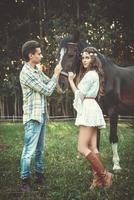 Young couple taking care about beautiful horse photo