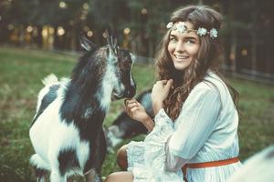 hermosa mujer con una divertida cabra amistosa en el pueblo foto