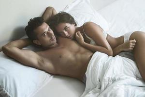 una pareja joven está acostada en la cama foto