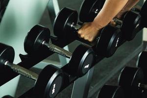 Closeup row of dumbbells and female hands photo