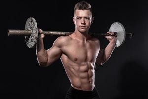 Young man bodybuilder with barbell in studio photo