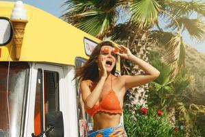 Happy young woman ice cream seller beside her old bus photo