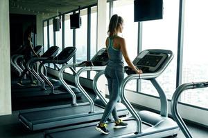 mujer joven y deportiva en cinta de correr en el gimnasio foto