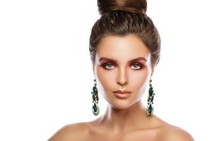 Beautiful woman with a colorful makeup is wearing earrings with green emeralds photo