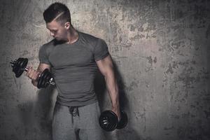 Young bodybuilder doing biceps curls with dumbbells photo