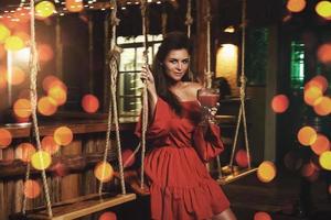 Charming woman wearing red dress in evening summer bar photo