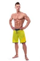 Modelo de fitness en shorts verdes sobre fondo blanco. foto