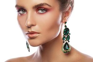 Beautiful woman with a colorful makeup is wearing earrings with green emeralds photo
