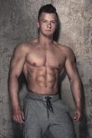 Handsome and muscular guy against concrete wall photo