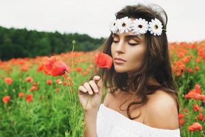 Beautiful woman in field with a lot of poppy flowers photo