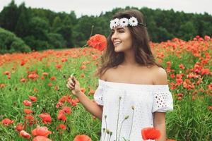 bella mujer en el campo con muchas flores de amapola foto