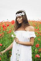 bella mujer en el campo con muchas flores de amapola foto