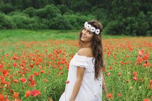 bella mujer en el campo con muchas flores de amapola foto