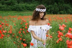 bella mujer en el campo con muchas flores de amapola foto