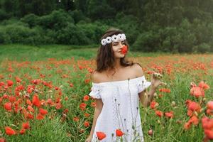 bella mujer en el campo con muchas flores de amapola foto