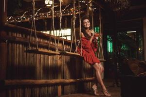 Charming woman wearing red dress in evening summer bar photo