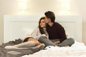 pareja joven con suéteres cálidos sentados en la cama foto