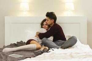 Young couple wearing warm sweaters sitting on the bed photo