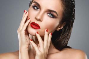 Portrait of beautiful young woman with a red lipstick and nail polish photo