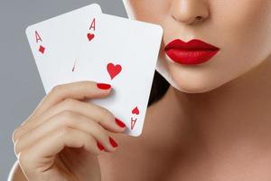 Woman with red lips is holding two aces. photo