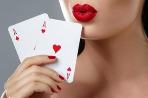 Woman with red lips is holding two aces. photo