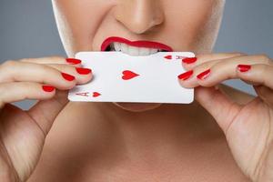 Woman with red lips is holding ace card in her hands photo