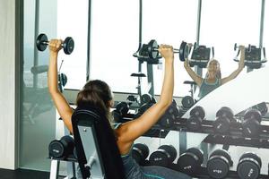 Woman working out with dumbbells in gym photo