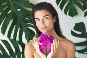 Young and beautiful woman with perfect smooth skin is holding orchid flowers photo