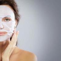 Woman with a cloth moisturizing mask on her face photo