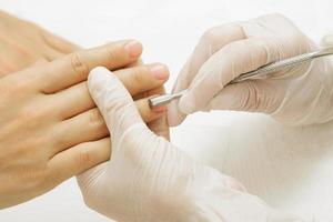 Manicure master work. Closeup of hands with a cuticle remover tool photo